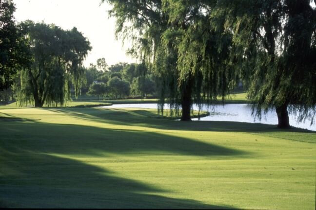 Tree-lined Hilldale fairway with water in the morning light
